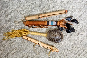 From top to bottom, a clapper stick, a deer hoof rattle, a turtle rattle, and a flute.